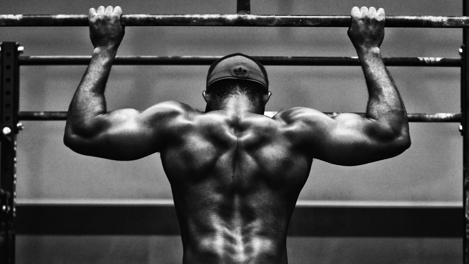 Lifter at the top of a pull-up seen from behind. Rating effort on sets like this is the first step in RPE for progressive overload